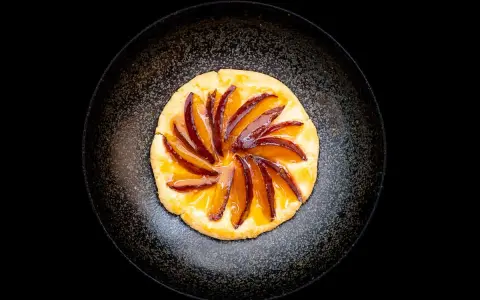 Eine köstliche Zwetschgen Tarte, mit saftigen Zwetschgenspalten, kunstvoll auf einem knusprigen Teig arrangiert und mit glänzendem Sirup überzogen.