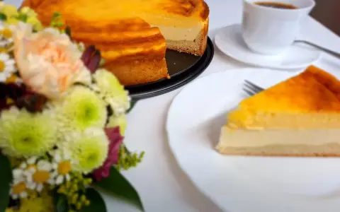 Ein köstliches Eierschecke-Rezept: Ein goldbrauner Kuchen mit cremiger Füllung, daneben eine Tasse Kaffee und ein Blumenstrauß.