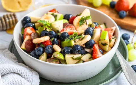 Ein bunter Obstsalat mit Erdbeeren, Blaubeeren, Bananen und Äpfeln, perfekt für ein leichtes obstsalat rezept.