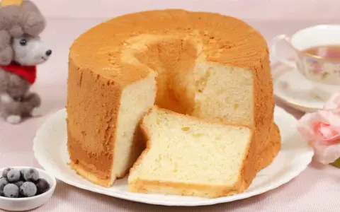 Ein luftiger Chiffon-Kuchen mit einer Scheibe daneben, serviert mit Beeren und Tee.
