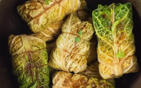 Gefüllte Kohlrouladen, ein Klassiker der wirsing rezepte, sind liebevoll mit Schnur gebunden und bereit zum Genuss.