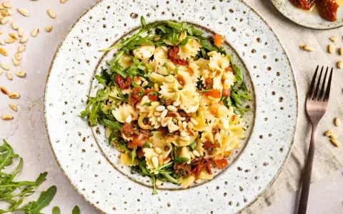 Mediterraner Salat mit Farfalle, getrockneten Tomaten, Rucola und Pinienkernen. Ein leichter Genuss!
