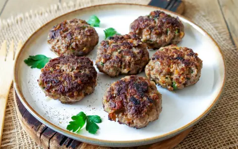 Sechs goldbraune Buletten, frisch gebraten, liegen auf einem Teller. Ein einfaches Buletten Rezept, das immer gelingt.