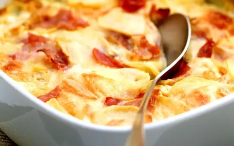 Schinken Sahne Auflauf ohne Vorkochen: Kartoffelscheiben mit Schinken und cremiger Sauce im Auflauf, bereit zum Servieren.