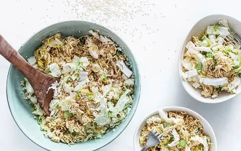 Ein großer Schüssel mit "friss dich dumm salat" aus Nudeln, Chinakohl und Frühlingszwiebeln, daneben zwei kleinere Schüsseln.