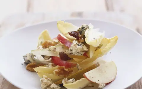 Ein köstlicher chicoree salat mit Äpfeln, Birnen, Blauschimmelkäse und Walnüssen auf einem weißen Teller.