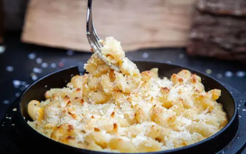 Ein Gabel hebt cremiges, überbackenes Mac n Cheese aus einer Pfanne. Dieses amerikanische Original-Rezept ist ein Genuss!