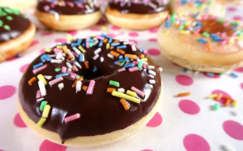 Bunte Streusel auf Schokoladen- und Zuckerguss-Donuts, die an ein leckeres Donut Teig Rezept erinnern.