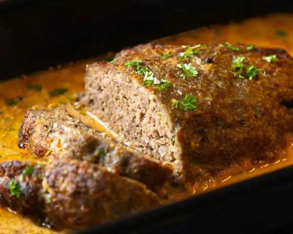 Saftiger Hackbraten mit cremiger Sauce, garniert mit Petersilie. Ein köstliches Hackbraten Rezept, das jeden begeistert.