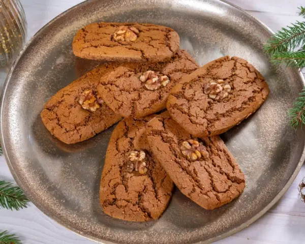 Aachener Printen Rezept: Köstliche, nussgekrönte Printen auf einem silbernen Teller, umgeben von Tannenzweigen und Zapfen. Perfekt für die Weihnachtszeit.