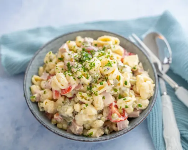 Schüssel mit cremigem Nudelsalat, garniert mit Petersilie. Das cremige nudelsalat dressing macht ihn unwiderstehlich.