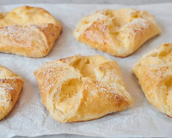 Goldbraune Quarktaschen, mit Puderzucker bestäubt, sehen aus wie ein köstliches Quarktaschen Rezept.