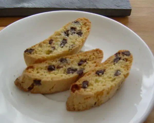 Drei knusprige Cantuccini mit Schokolade liegen auf einem weißen Teller.