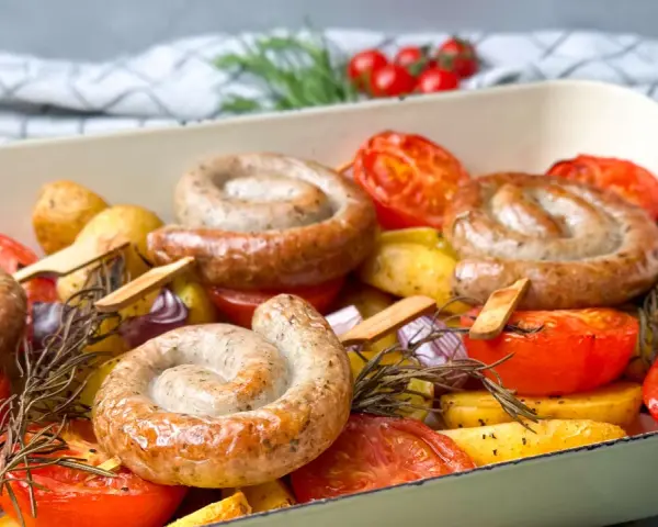 Bratwurst-Ringe mit Kartoffeln, Tomaten und Rosmarin im Ofen gebacken.