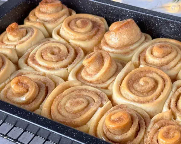 Frisch gebackene Zimtschnecken in einer Backform, goldbraun und duftend.