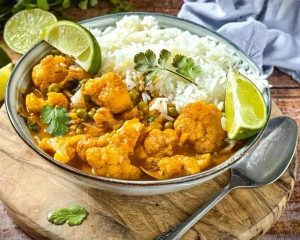 Herzhaftes Curry mit Blumenkohl und Reis, garniert mit Limettenspalten. Ein köstliches Beispiel für Blumenkohl Rezepte.