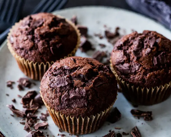 Drei saftige Schokomuffins mit Schokoladenstückchen, perfekt für ein schnelles schokomuffins rezept.