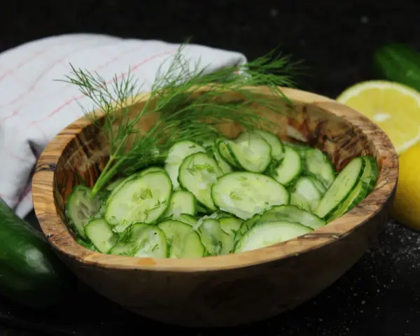 Frischer Gurkensalat im Holzschälchen, garniert mit Dill. Ein einfaches gurkensalat rezept für den Sommer.