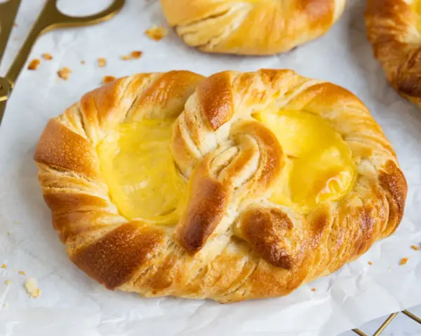 Goldene puddingbrezeln, frisch gebacken, warten auf das puddingbrezel rezept. Daneben liegt eine goldene Zange.