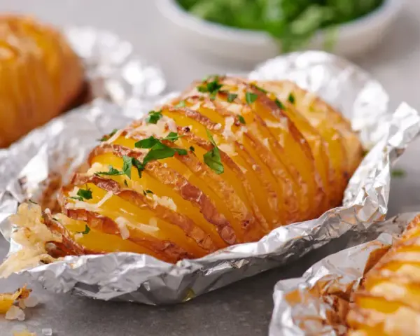 Leckere Hasselback-Kartoffeln, bestreut mit Käse und Petersilie. Ein einfaches Gericht aus der Kategorie Kartoffel Rezepte.