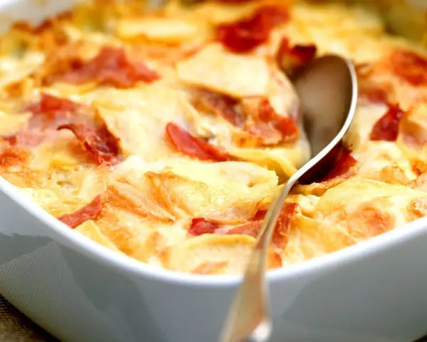 Schinken Sahne Auflauf ohne Vorkochen: Kartoffelscheiben mit Schinken und cremiger Sauce im Auflauf, bereit zum Servieren.