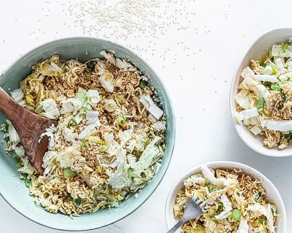 Ein großer Schüssel mit "friss dich dumm salat" aus Nudeln, Chinakohl und Frühlingszwiebeln, daneben zwei kleinere Schüsseln.