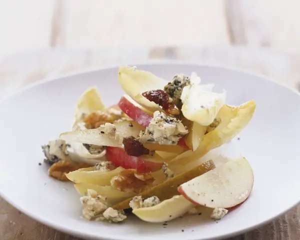 Ein köstlicher chicoree salat mit Äpfeln, Birnen, Blauschimmelkäse und Walnüssen auf einem weißen Teller.