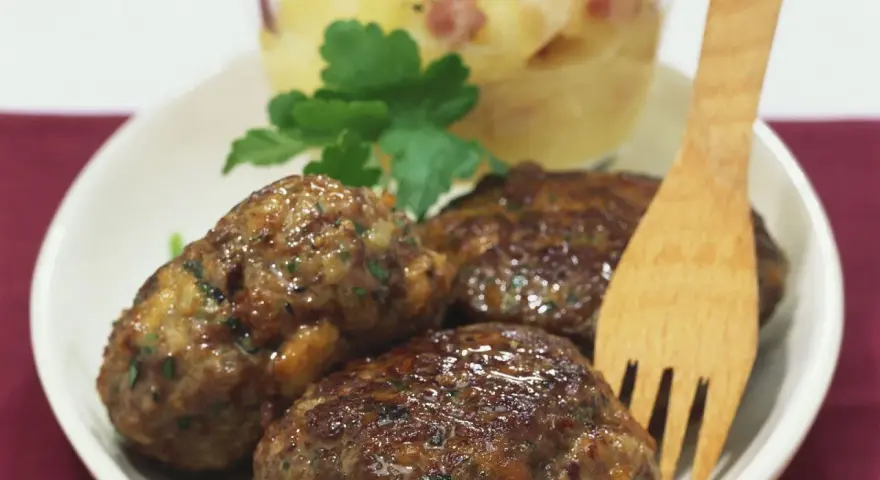 Saftige Frikadellen mit cremigem Kartoffelsalat, garniert mit Petersilie. Ein klassisches Gericht, das immer schmeckt.