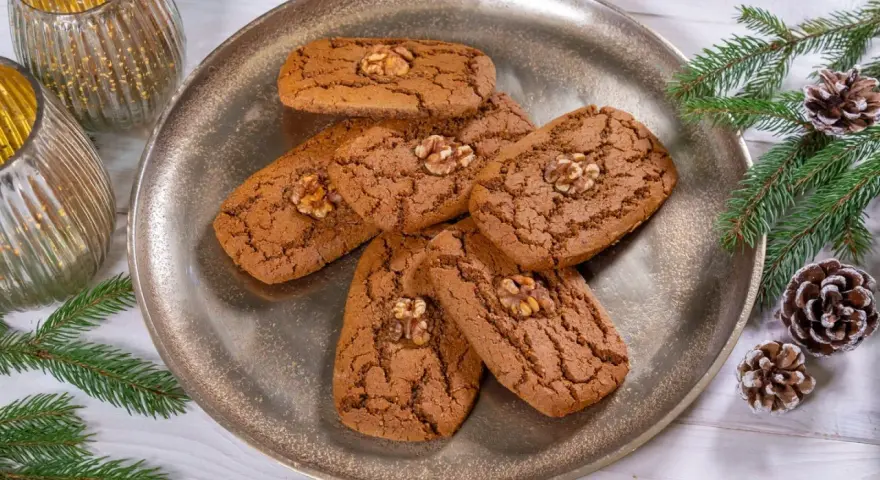 Aachener Printen Rezept: Köstliche, nussgekrönte Printen auf einem silbernen Teller, umgeben von Tannenzweigen und Zapfen. Perfekt für die Weihnachtszeit.