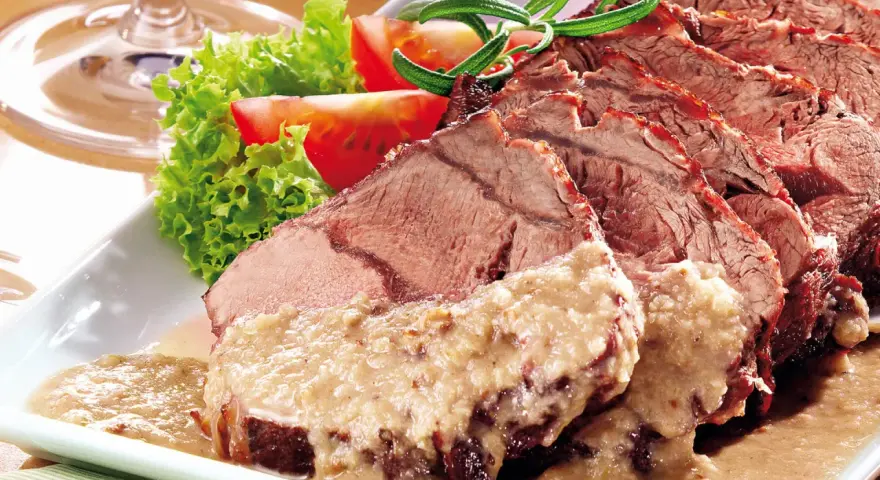 Saftiger Sauerbraten, perfekt für Ihr nächstes Sauerbraten Rezept, serviert mit frischem Salat und Tomaten.