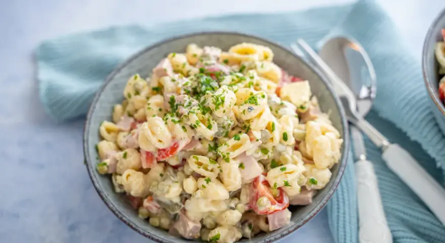 Schüssel mit cremigem Nudelsalat, garniert mit Petersilie. Das cremige nudelsalat dressing macht ihn unwiderstehlich.