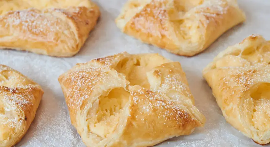 Goldbraune Quarktaschen, mit Puderzucker bestäubt, sehen aus wie ein köstliches Quarktaschen Rezept.