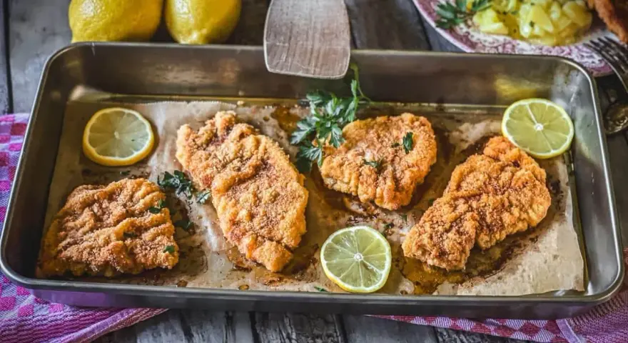 Saftiges Schnitzel im Backofen, goldbraun paniert, mit frischer Petersilie und Zitronenspalten garniert. Ein Genuss!