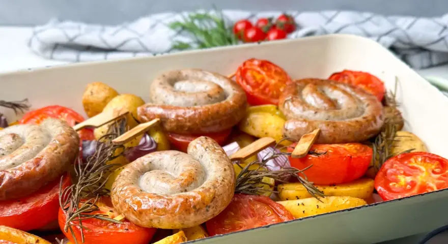 Bratwurst-Ringe mit Kartoffeln, Tomaten und Rosmarin im Ofen gebacken.
