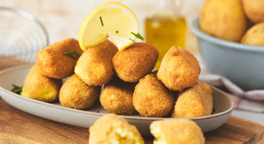 Goldbraune, knusprige Kroketten, frisch zubereitet, mit Zitrone und Kräutern garniert. Perfekt zum Selbermachen!
