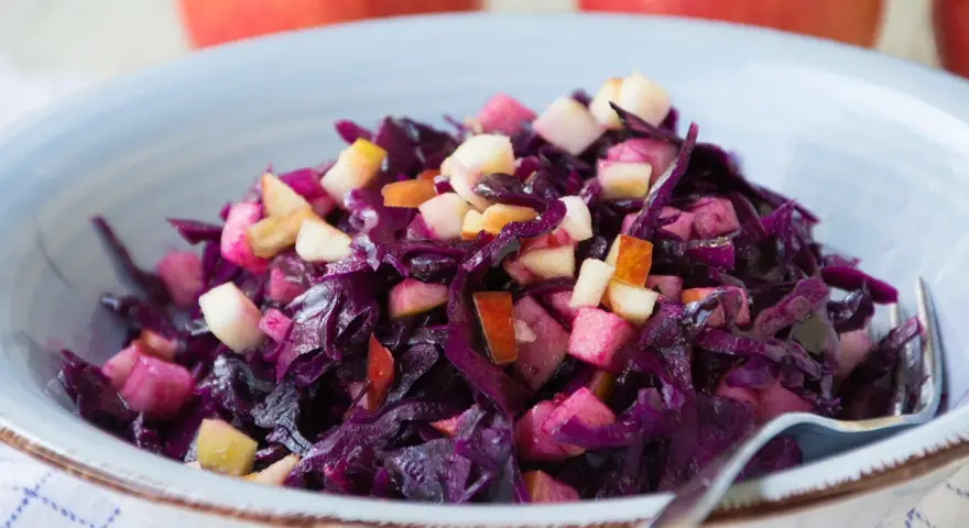 Schüssel mit leckerem rotkohl salat und Apfelstücken. Ein Klassiker, der immer schmeckt.
