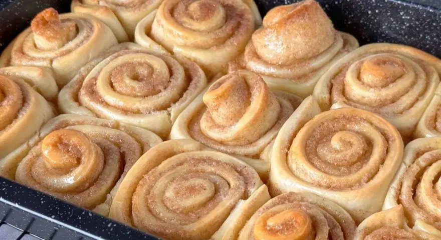 Frisch gebackene Zimtschnecken in einer Backform, goldbraun und duftend.