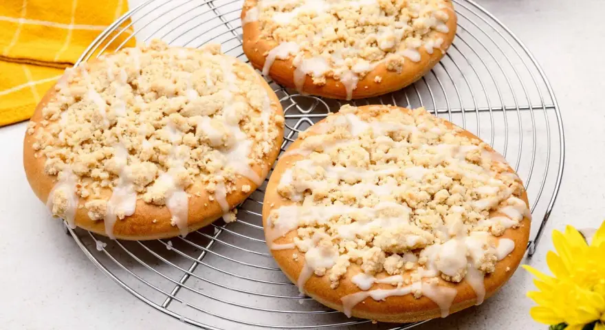 Drei runde Streusel Taler mit Zuckerguss auf einem Kuchengitter, bereit zum Genießen.