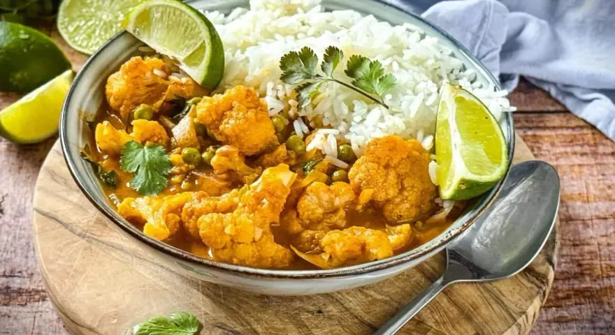 Herzhaftes Curry mit Blumenkohl und Reis, garniert mit Limettenspalten. Ein köstliches Beispiel für Blumenkohl Rezepte.
