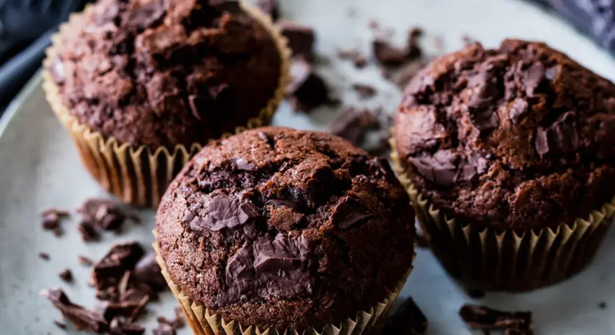 Drei saftige Schokomuffins mit Schokoladenstückchen, perfekt für ein schnelles schokomuffins rezept.