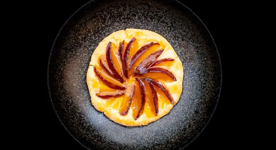 Eine köstliche Zwetschgen Tarte, mit saftigen Zwetschgenspalten, kunstvoll auf einem knusprigen Teig arrangiert und mit glänzendem Sirup überzogen.