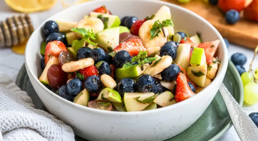 Ein bunter Obstsalat mit Erdbeeren, Blaubeeren, Bananen und Äpfeln, perfekt für ein leichtes obstsalat rezept.