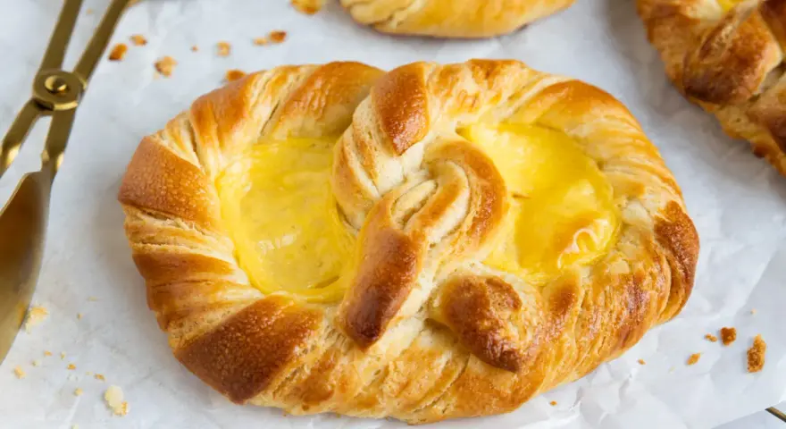 Goldene puddingbrezeln, frisch gebacken, warten auf das puddingbrezel rezept. Daneben liegt eine goldene Zange.