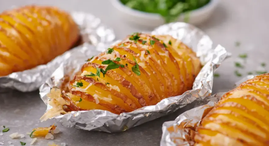 Leckere Hasselback-Kartoffeln, bestreut mit Käse und Petersilie. Ein einfaches Gericht aus der Kategorie Kartoffel Rezepte.