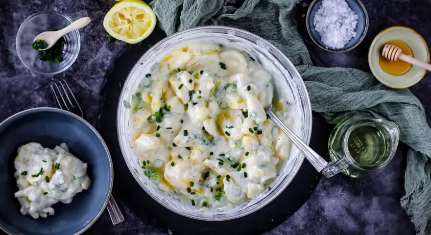 Cremiger Kartoffelsalat mit Joghurt, garniert mit Schnittlauch. Dazu Zitrone, Honig und grobes Salz.
