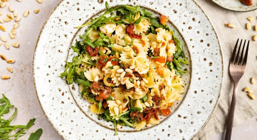 Mediterraner Salat mit Farfalle, getrockneten Tomaten, Rucola und Pinienkernen. Ein leichter Genuss!