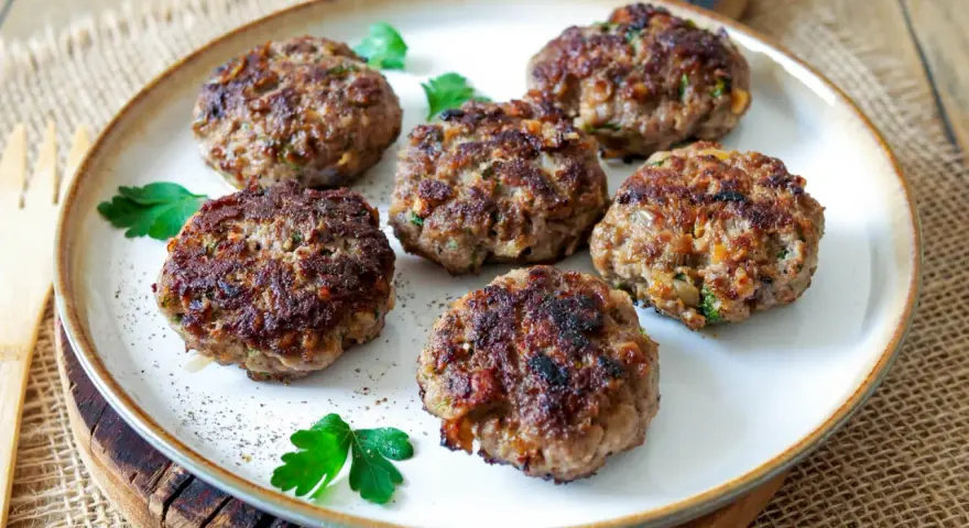 Sechs goldbraune Buletten, frisch gebraten, liegen auf einem Teller. Ein einfaches Buletten Rezept, das immer gelingt.