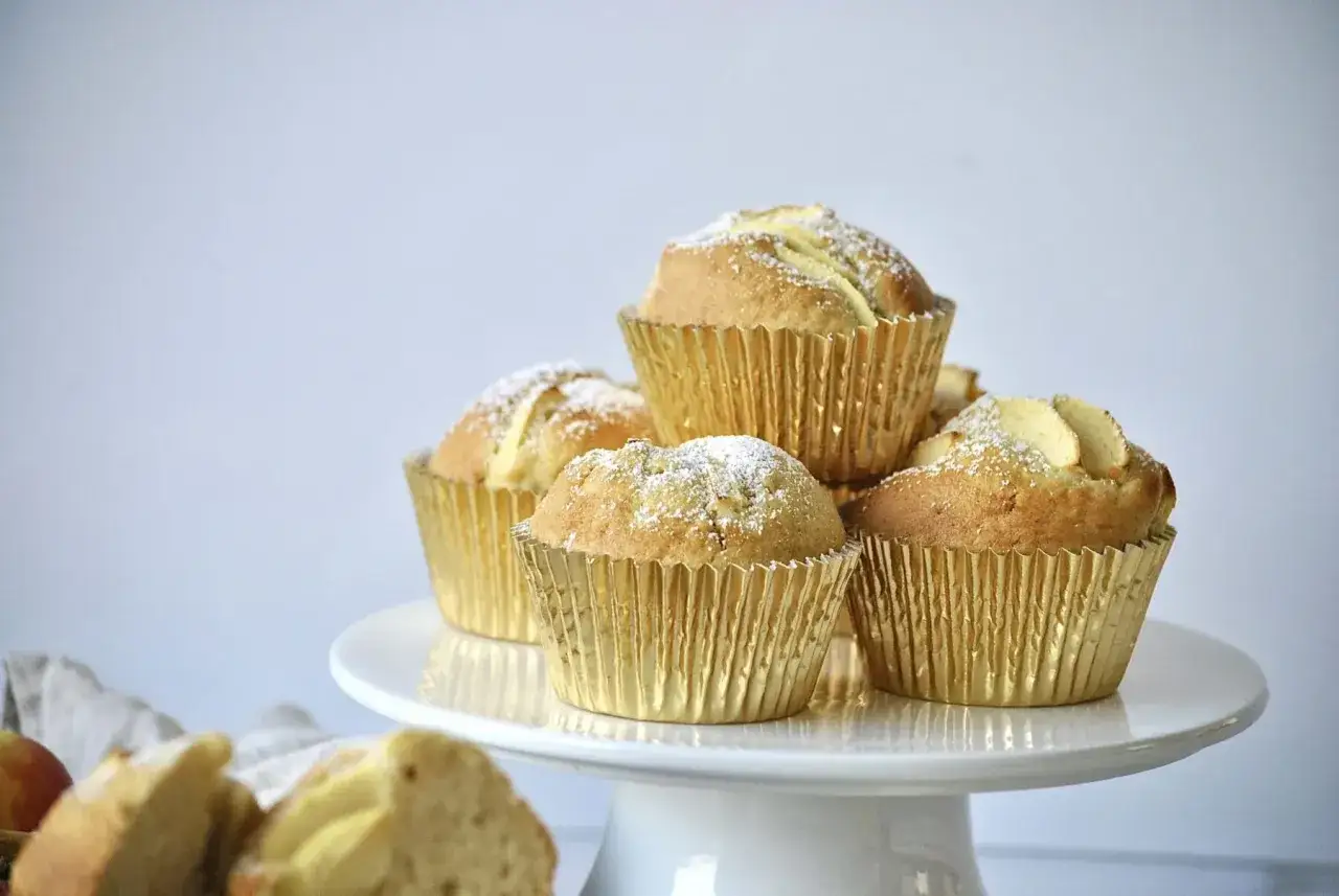 Goldene Muffins mit Apfelst&uuml;cken und Puderzucker, perfekt f&uuml;r ein Apfelmuffins Rezept.