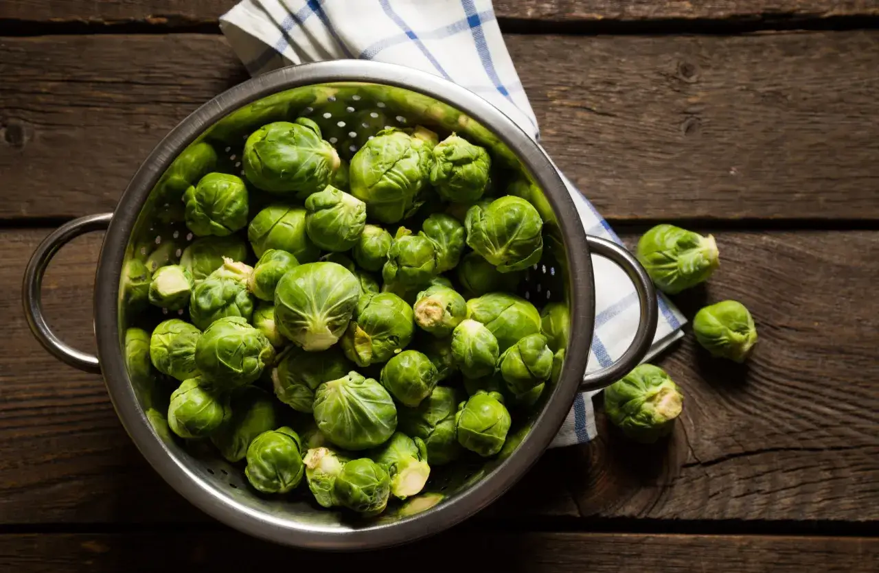 Frischer Rosenkohl in einem Sieb auf rustikalem Holztisch, bereit f&uuml;r leckere Rezepte mit Rosenkohl.