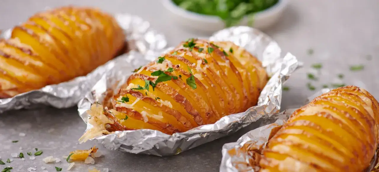Ofenfrische Hasselback-Kartoffeln, mit Käse und Petersilie bestreut. Ein einfaches und leckeres Gericht, das perfekt zu vielen kartoffel rezepte passt.